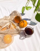 oranges in a net bag near mug of tea